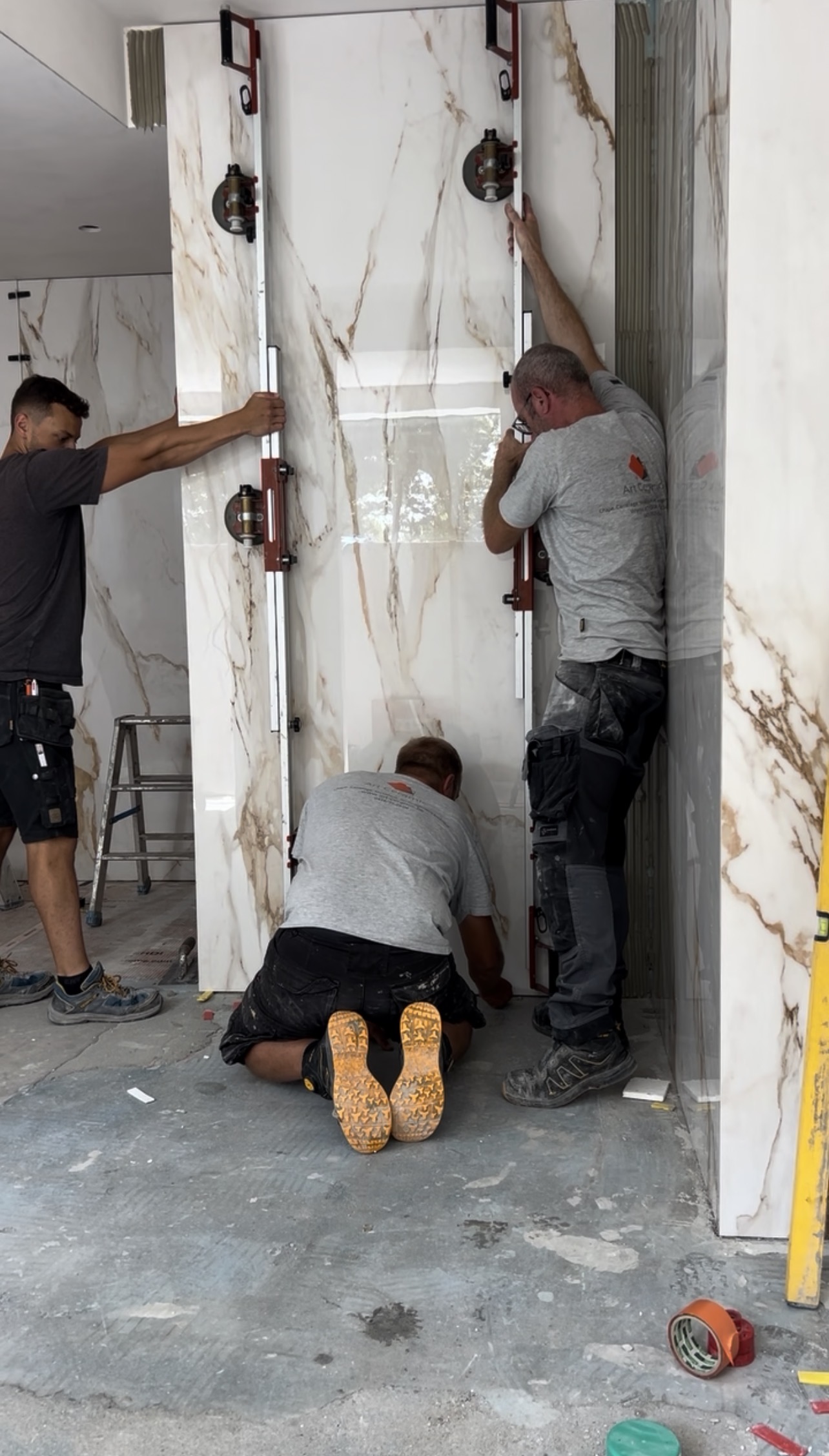 La pose de carrelage grand format demande une vraie organisation, du matériel adapté et souvent un travail à plusieurs. Texte alt : pose de carrelage grand format au mur avec cadre de manutention